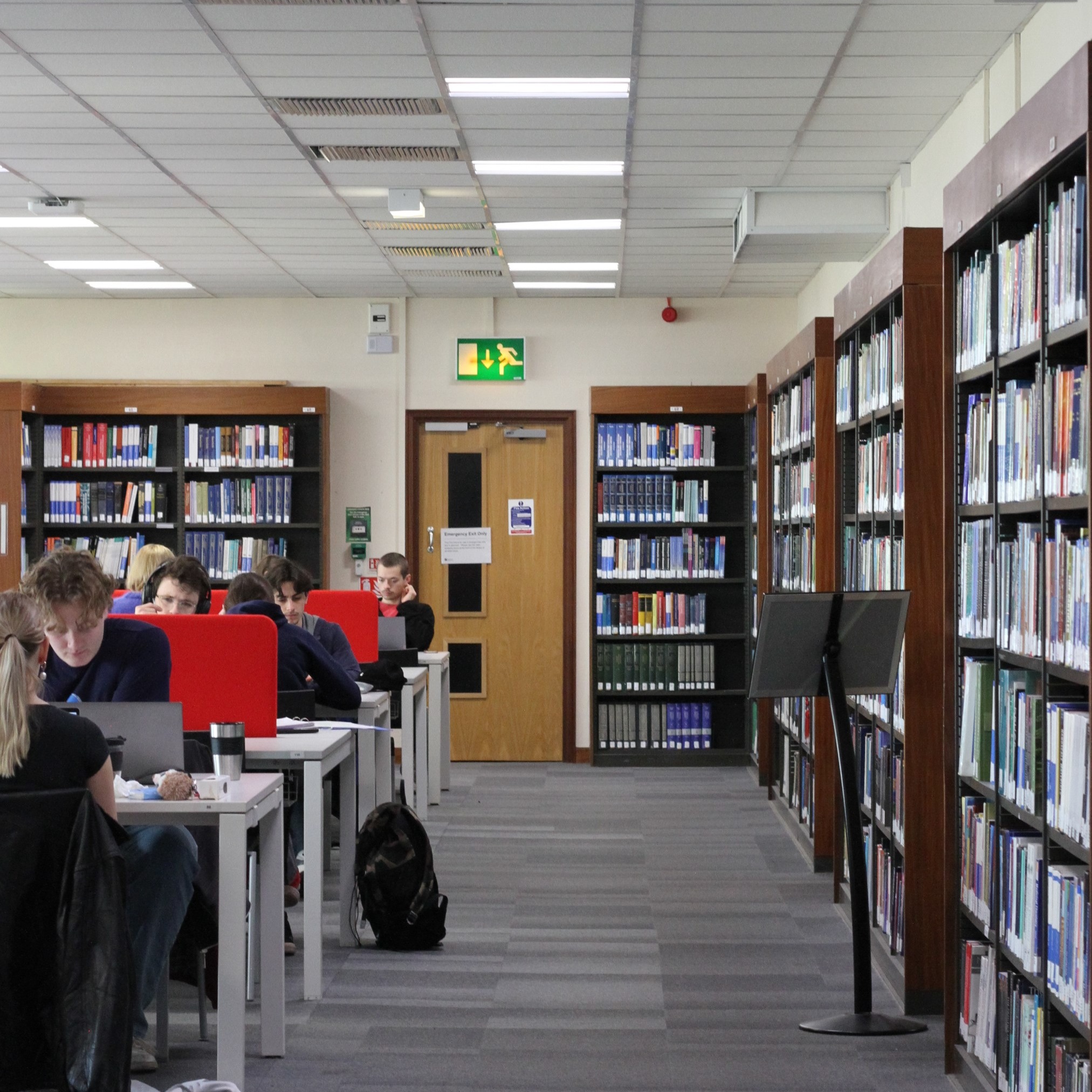 Students seated at desk in the Chemistry Library, next to shelves of books